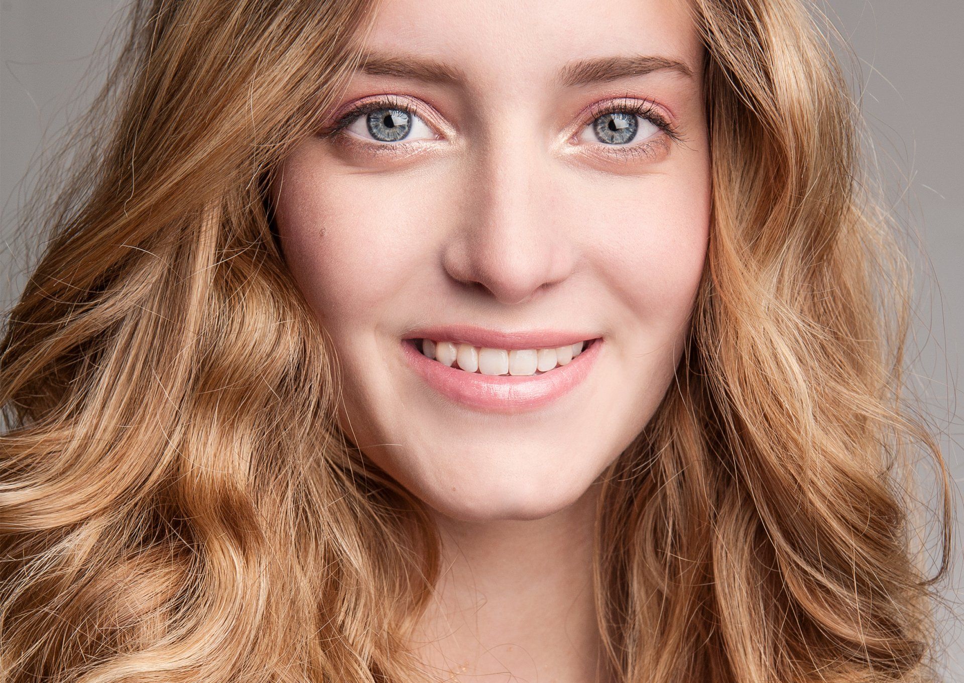 Eine Nahaufnahme des Gesichts einer lächelnden Frau mit langen blonden Haaren.