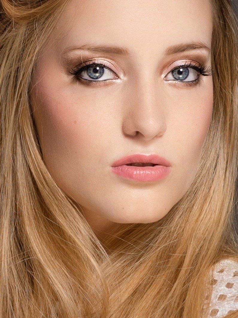 Eine Nahaufnahme des Gesichts einer Frau mit langen blonden Haaren und blauen Augen.