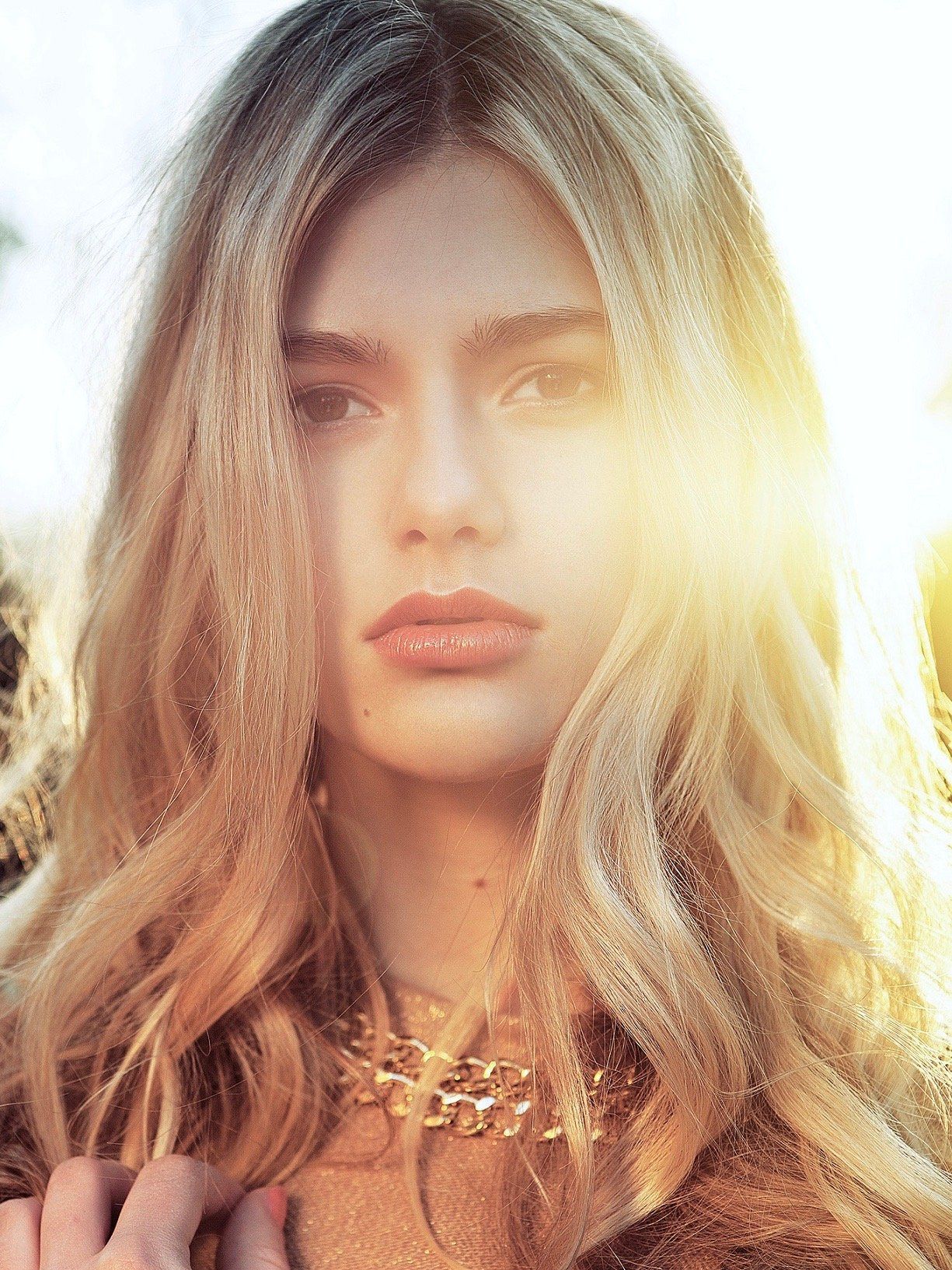 Eine Nahaufnahme des Gesichts einer Frau mit langen blonden Haaren und einer Halskette.