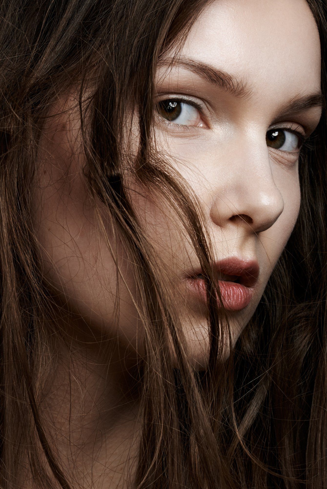 Eine Nahaufnahme des Gesichts einer Frau, deren Haare im Wind wehen.
