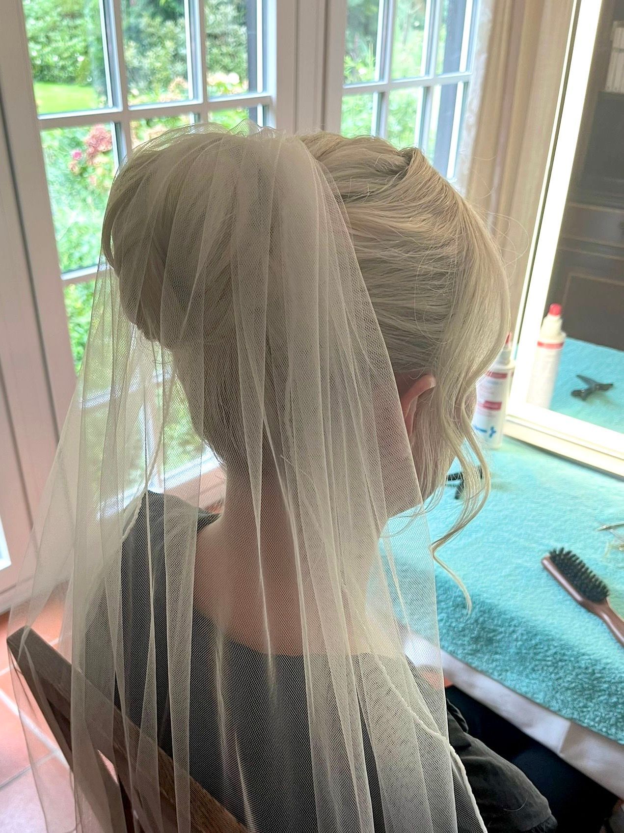 Eine Frau mit Schleier sitzt vor einem Fenster.