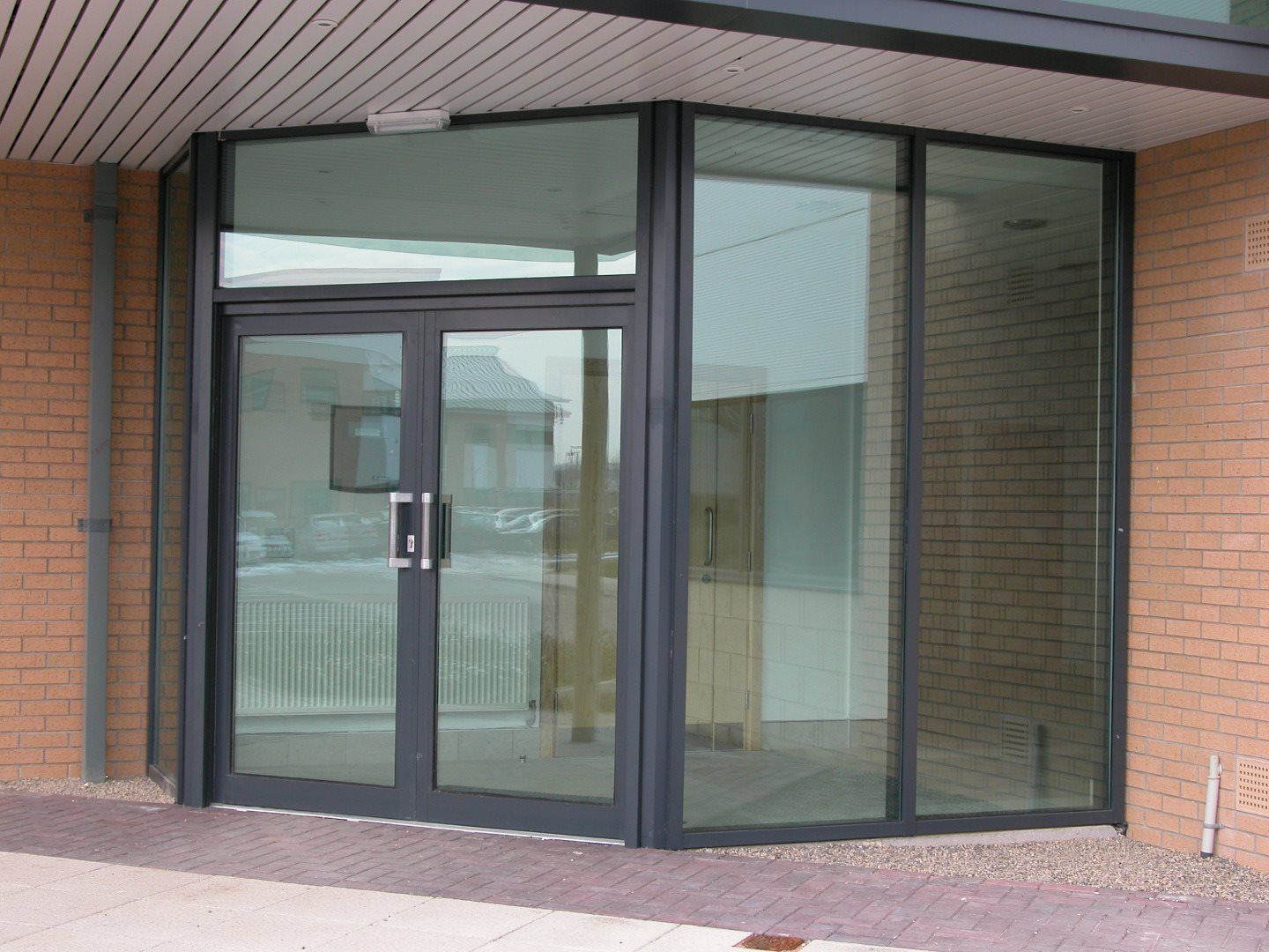 Glass and metal entryway with automatic doors; brick building.