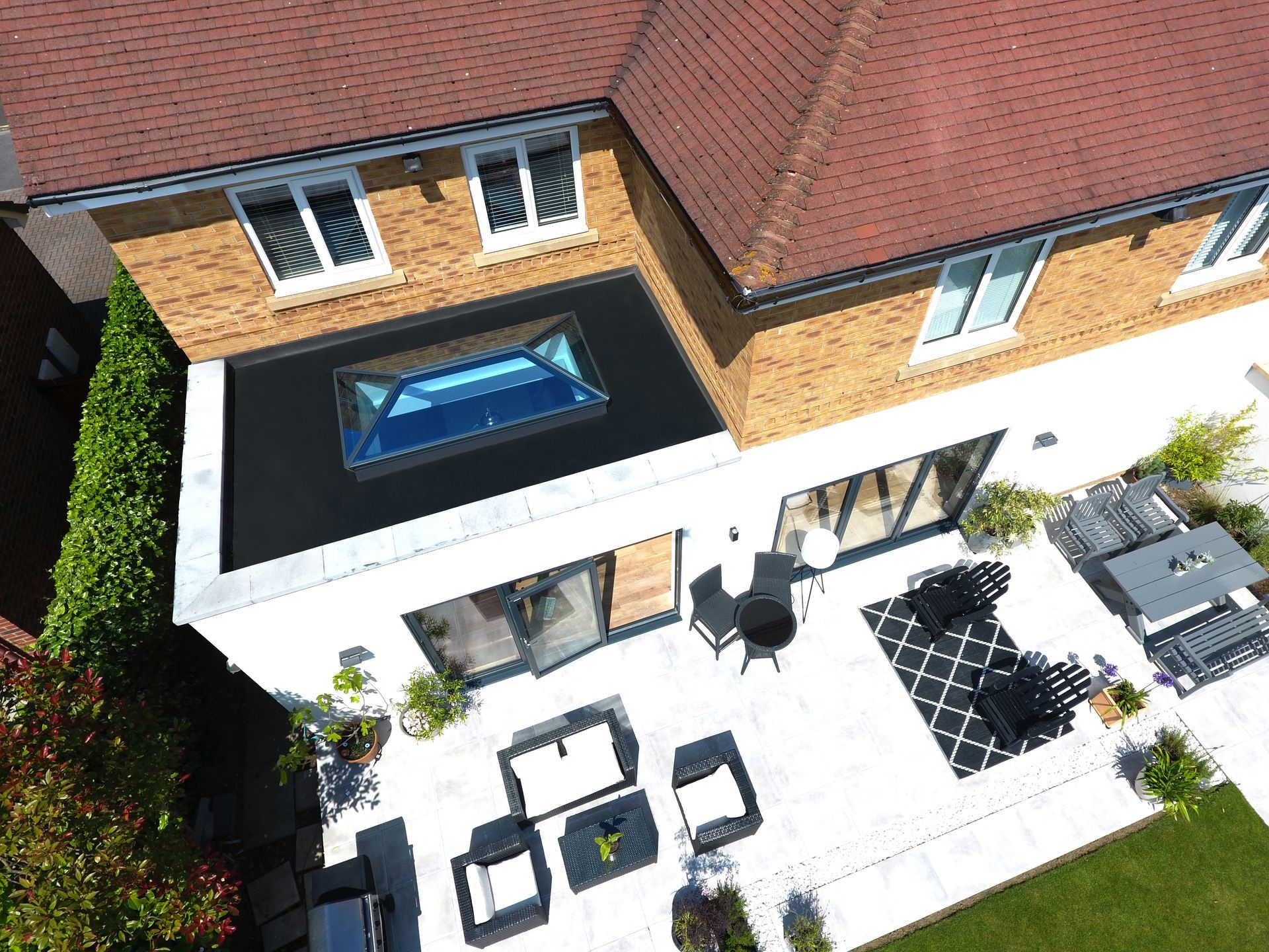 Aerial view of modern house with patio, skylight, and outdoor seating.