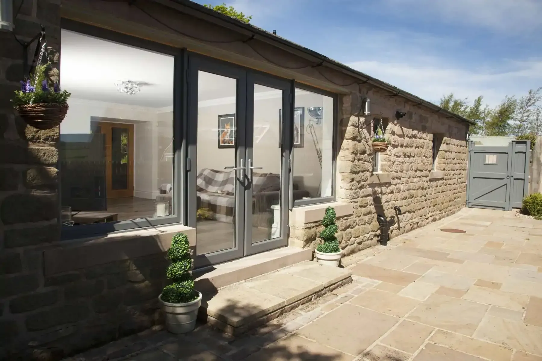 Stone building with large gray glass doors, patio, and a small gate.