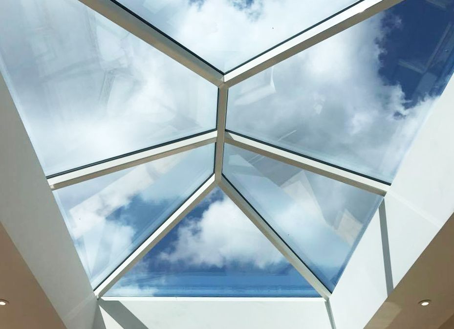 Skylight with a geometric design, offering a view of a cloudy blue sky.