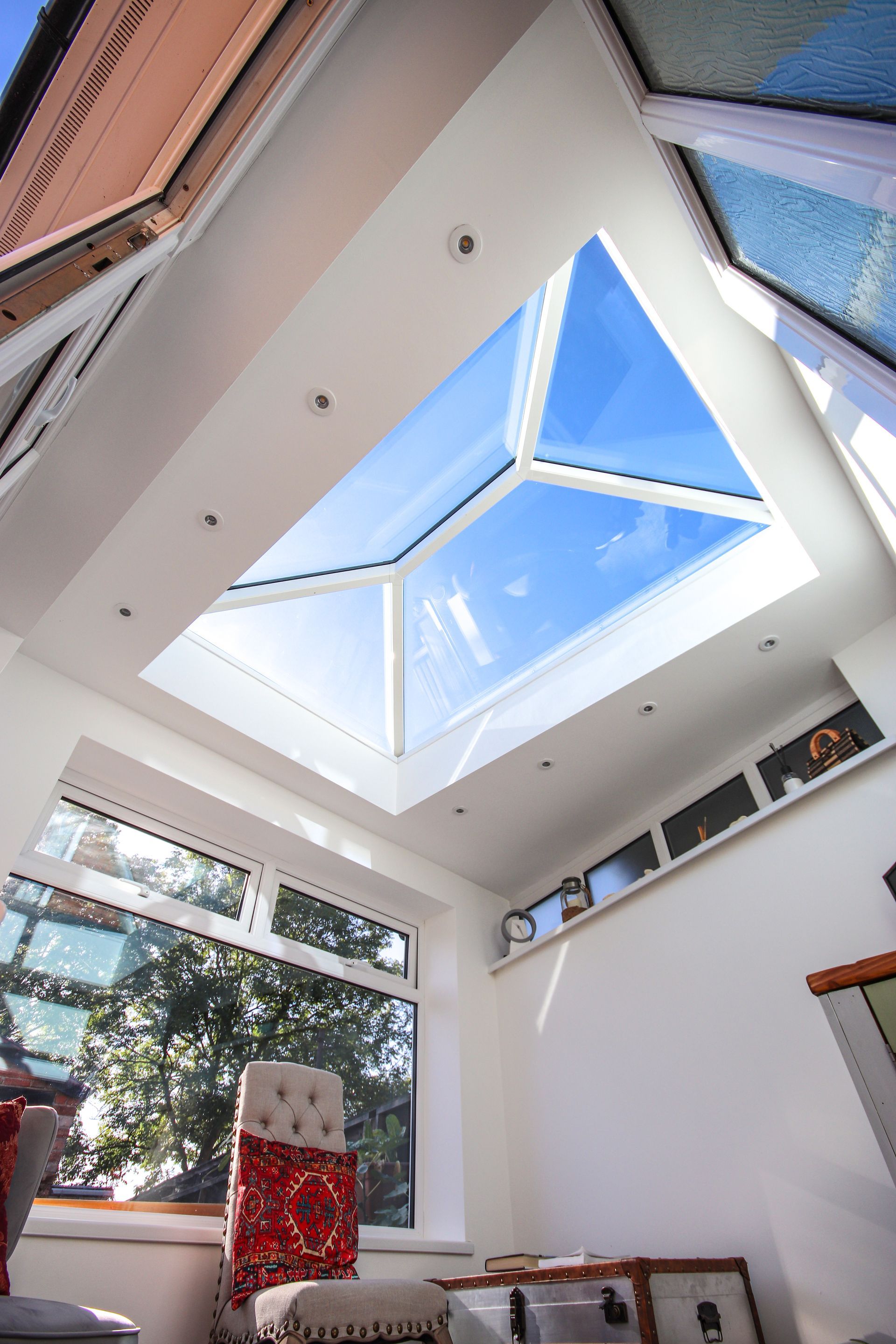 Interior view of a bright room with a large skylight, white walls, and a view of the blue sky.