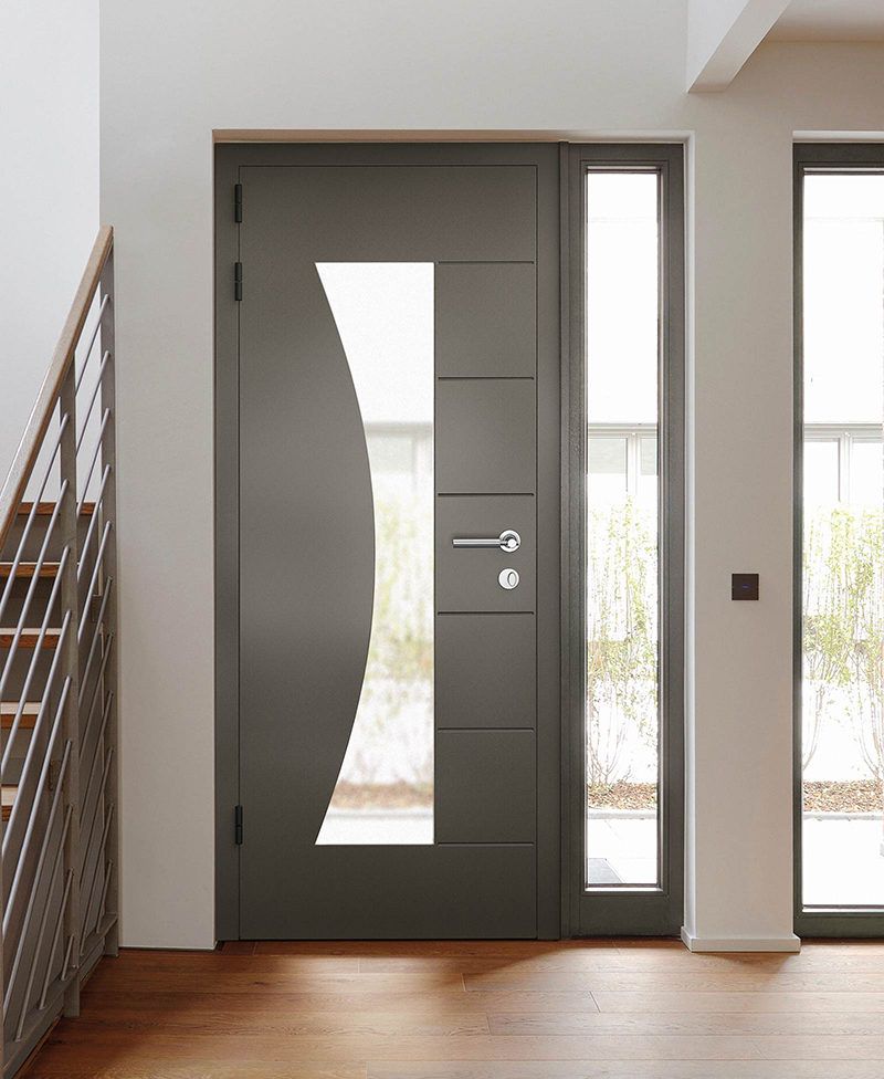 Dark gray front door with large curved window, sidelight, and wood floor.