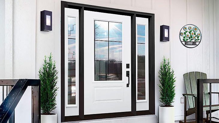 White front door with sidelights, black trim, sconces, and potted greenery.