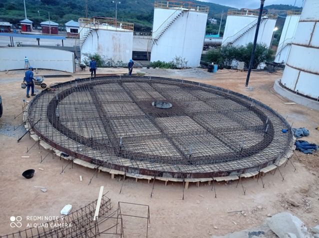 Obreros soldando vigas de acero en una obra bajo una estructura metálica; saltan chispas.