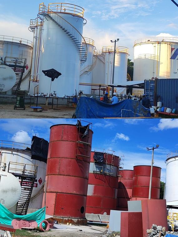 Tanques de almacenamiento industrial en un patio, incluyendo grandes tanques cilíndricos blancos y rojos con daños visibles.