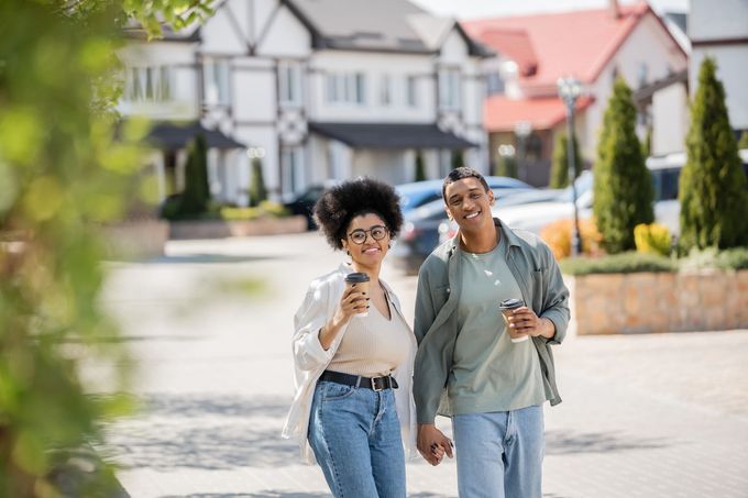 A man and a woman are walking down the street holding hands near River Place Flats