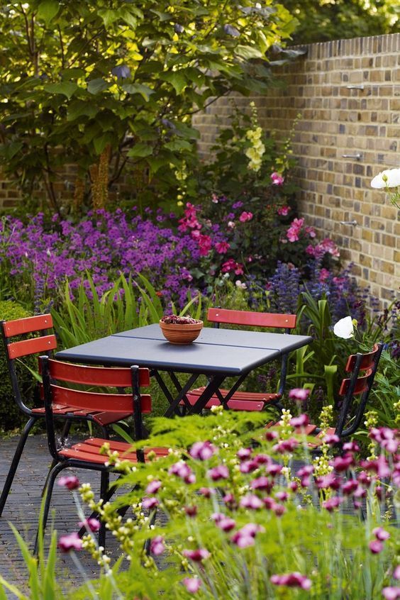 Une table et des chaises dans un jardin avec des fleurs violettes