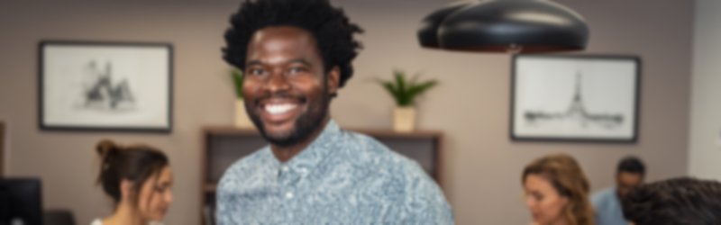 A man is smiling in front of a group of people in a room.