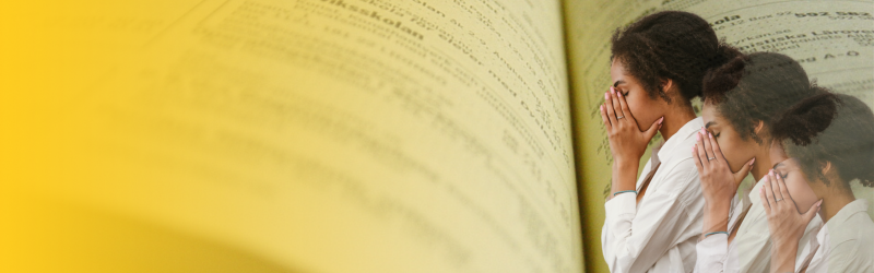 A woman is covering her face with her hands while reading a book.