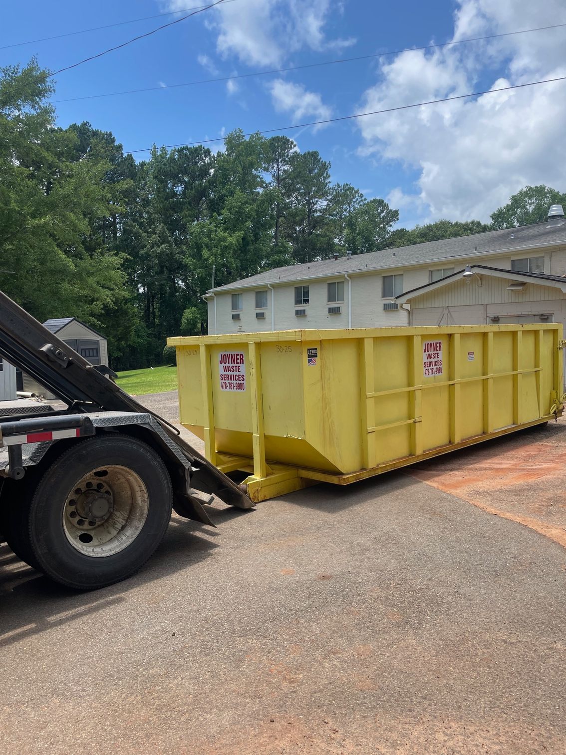 A large dumpster is parked in front of a building under construction.