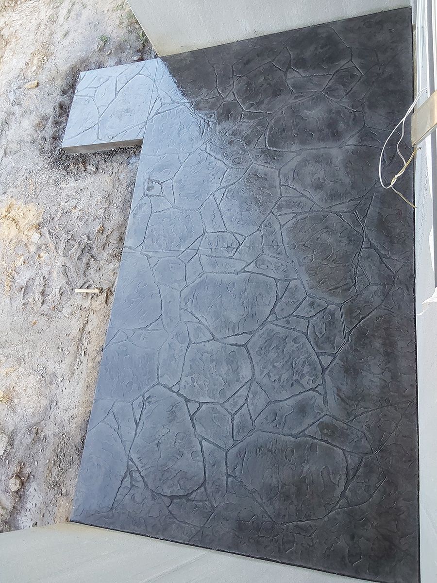 A black tile is sitting on top of a concrete floor.
