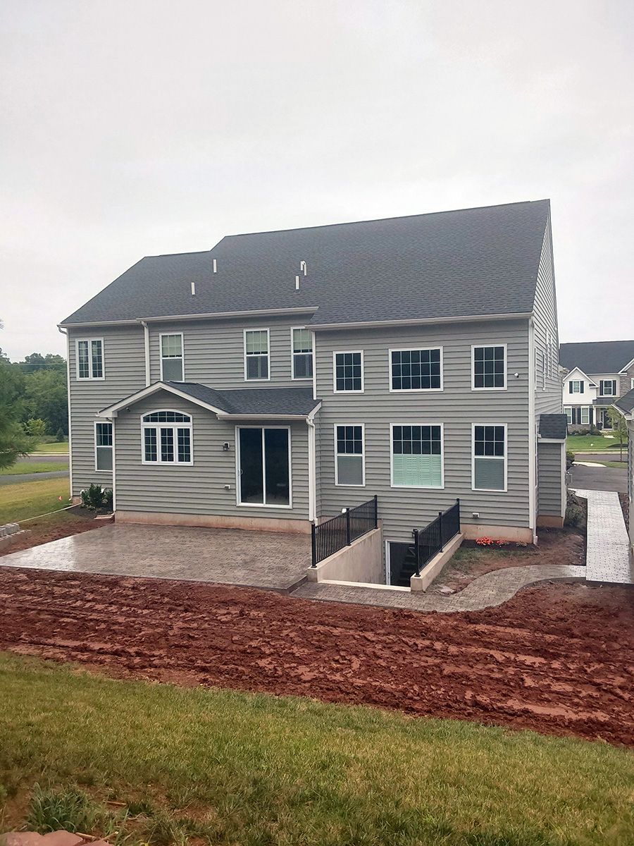 A large house with a lot of windows is sitting on top of a dirt field.