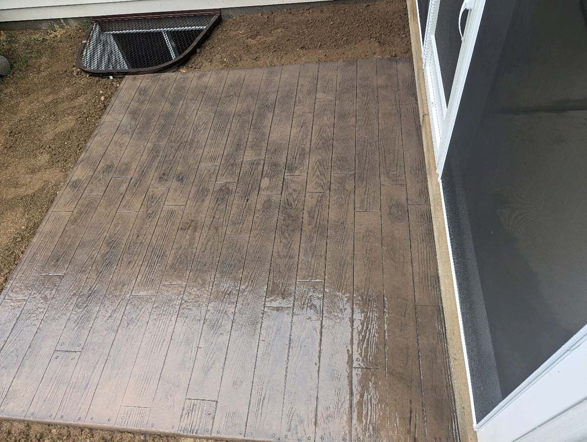 A concrete floor next to a screened in porch with a door mat on it.