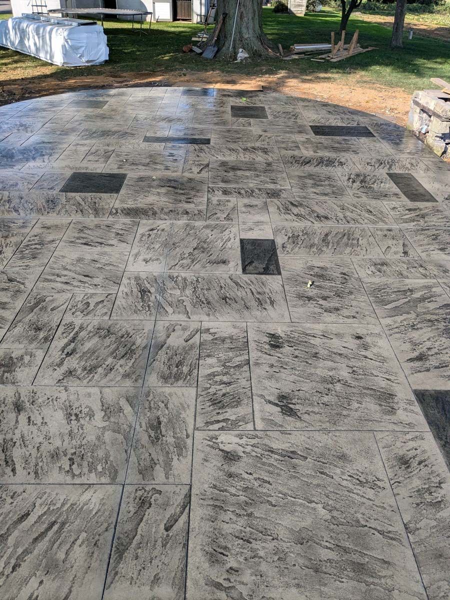 A concrete patio with a tree in the background.