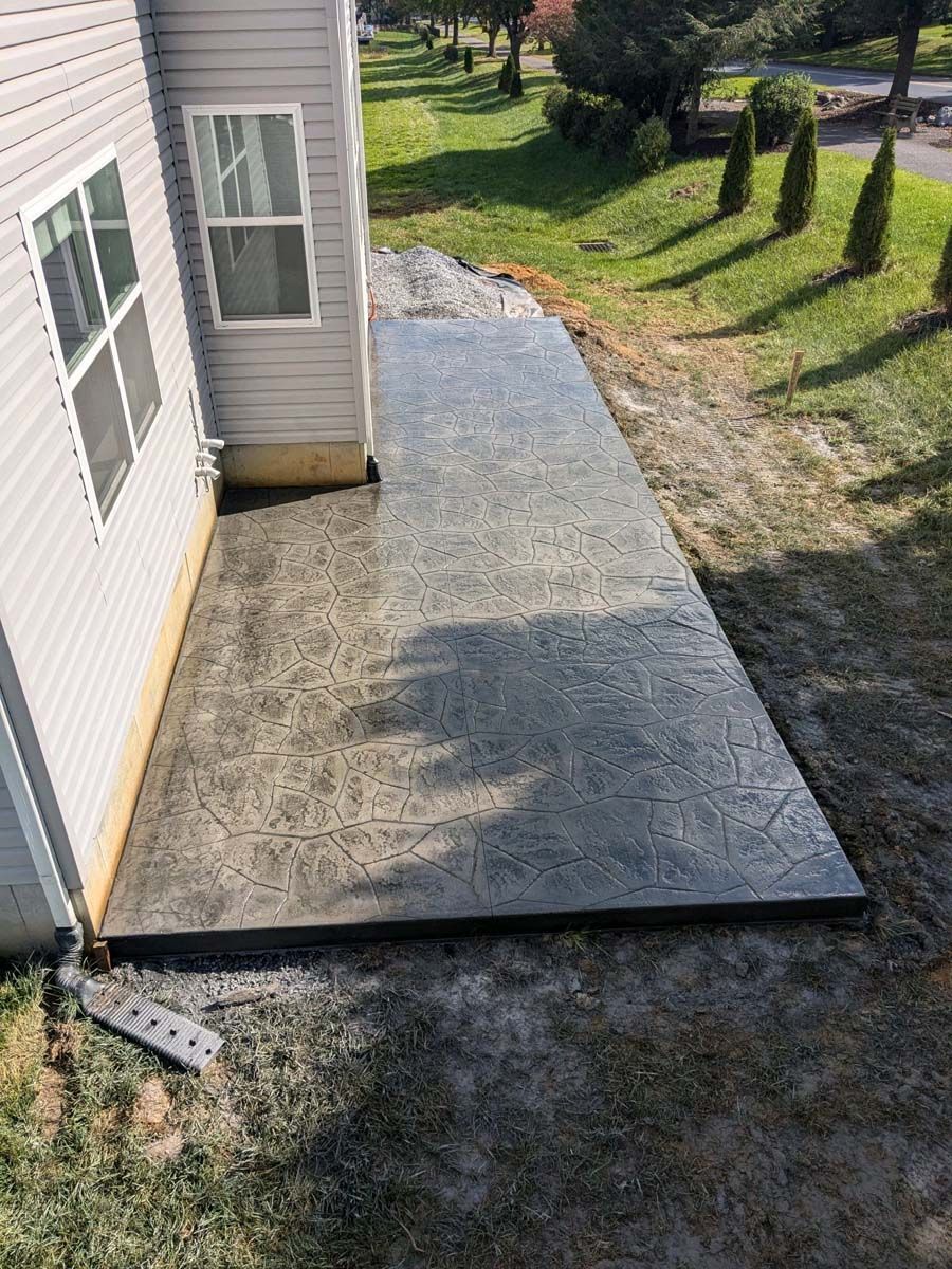 A concrete walkway is being built next to a house.