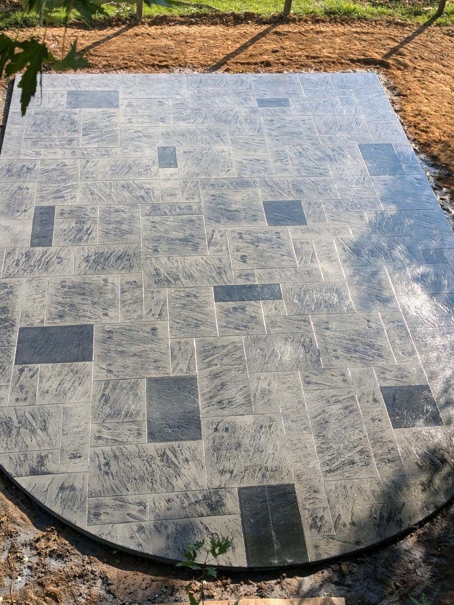 A concrete patio with a round table in the middle of it