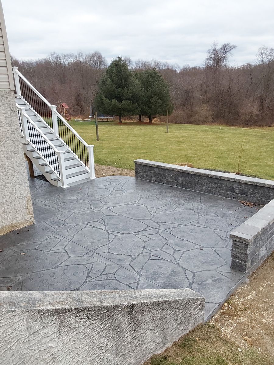 A patio with stairs leading up to it and a field in the background.