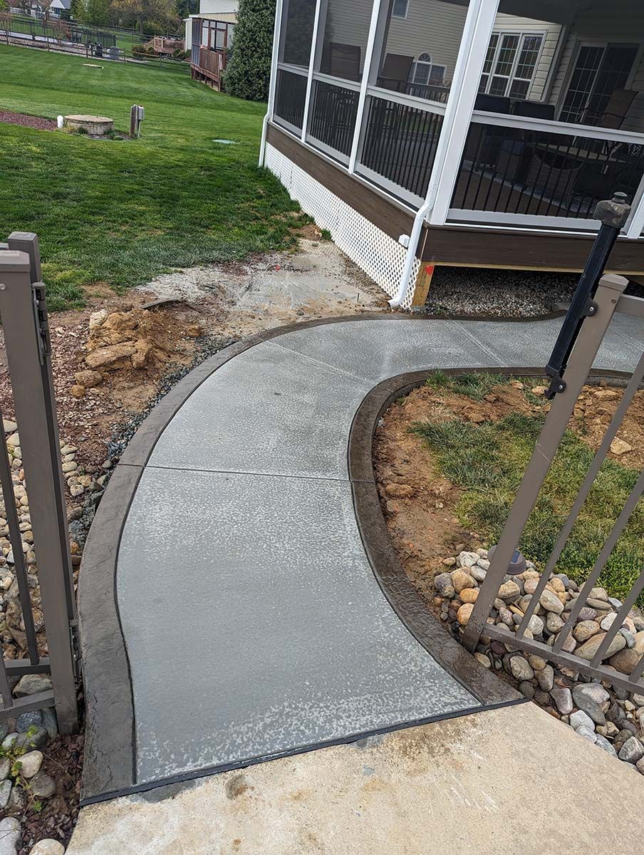 A concrete walkway leading to a screened in porch.