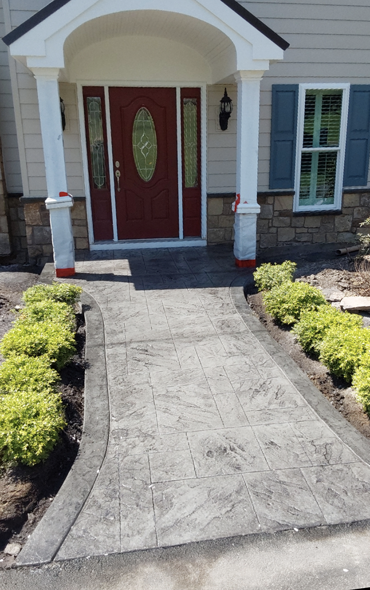 A concrete walkway leading to the front door of a house.