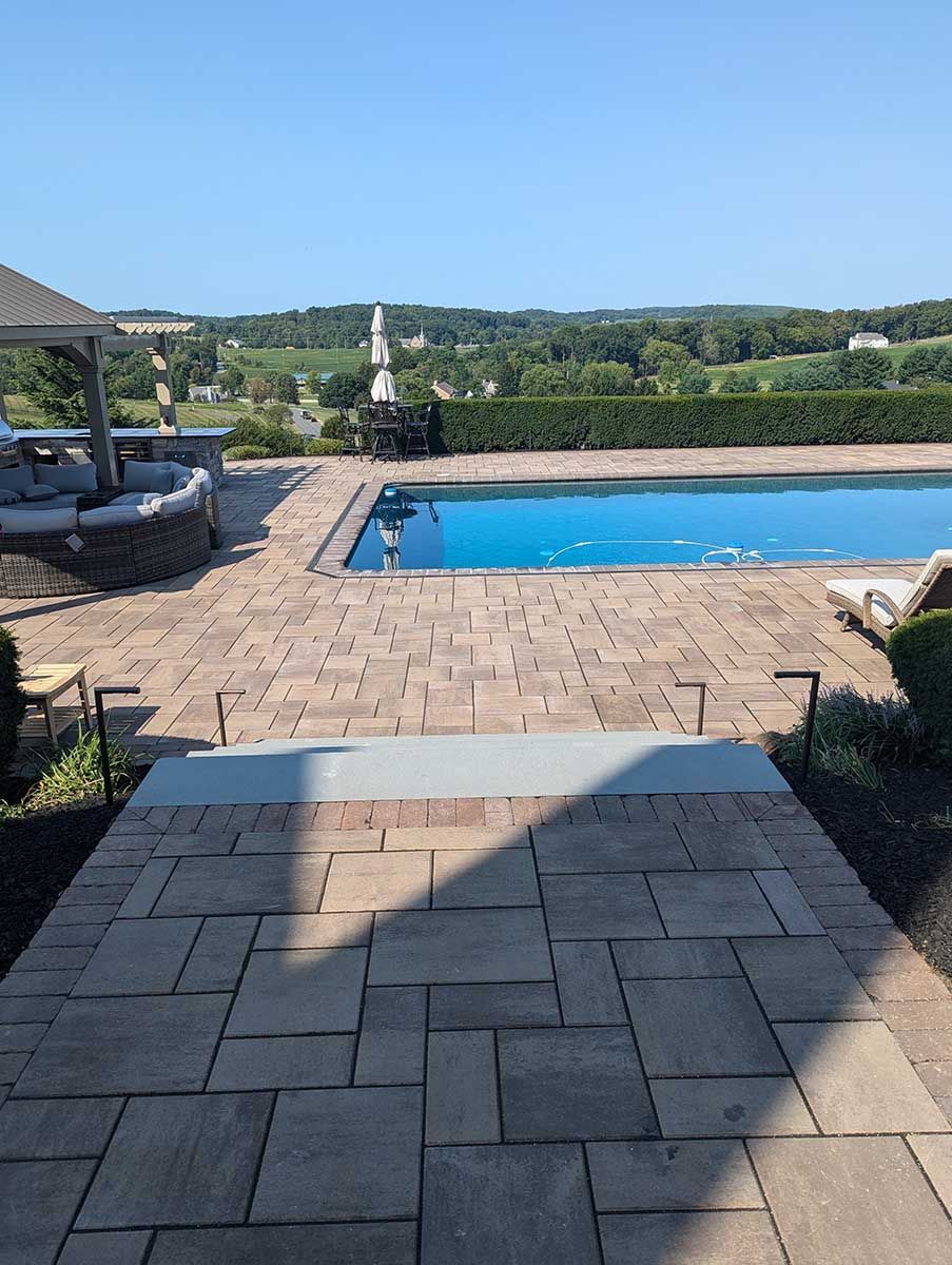 A patio with a large swimming pool in the background