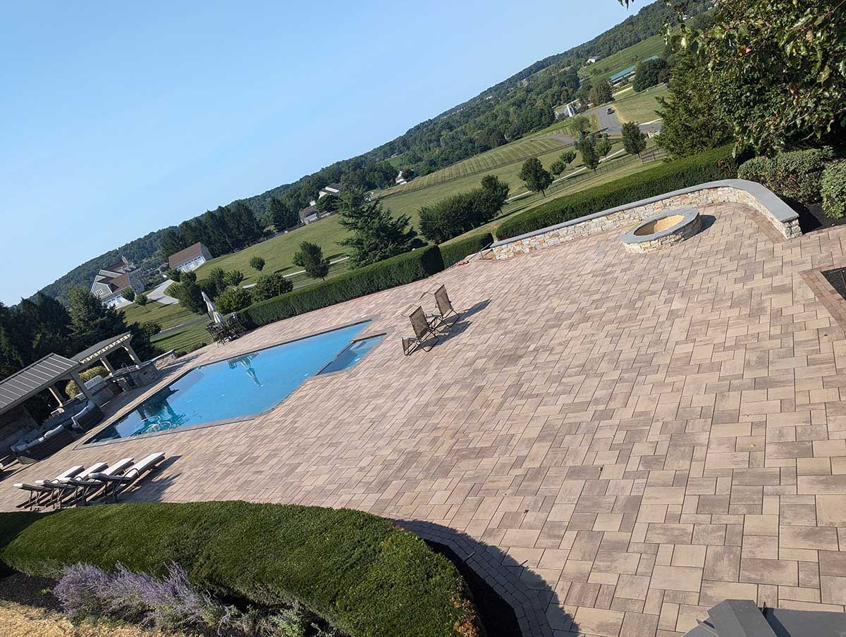 A large swimming pool is surrounded by a brick patio