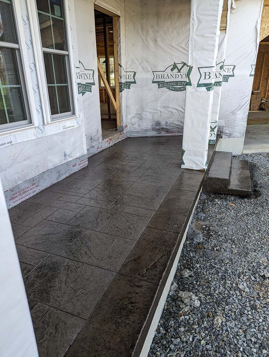 A concrete walkway leading to a house under construction.