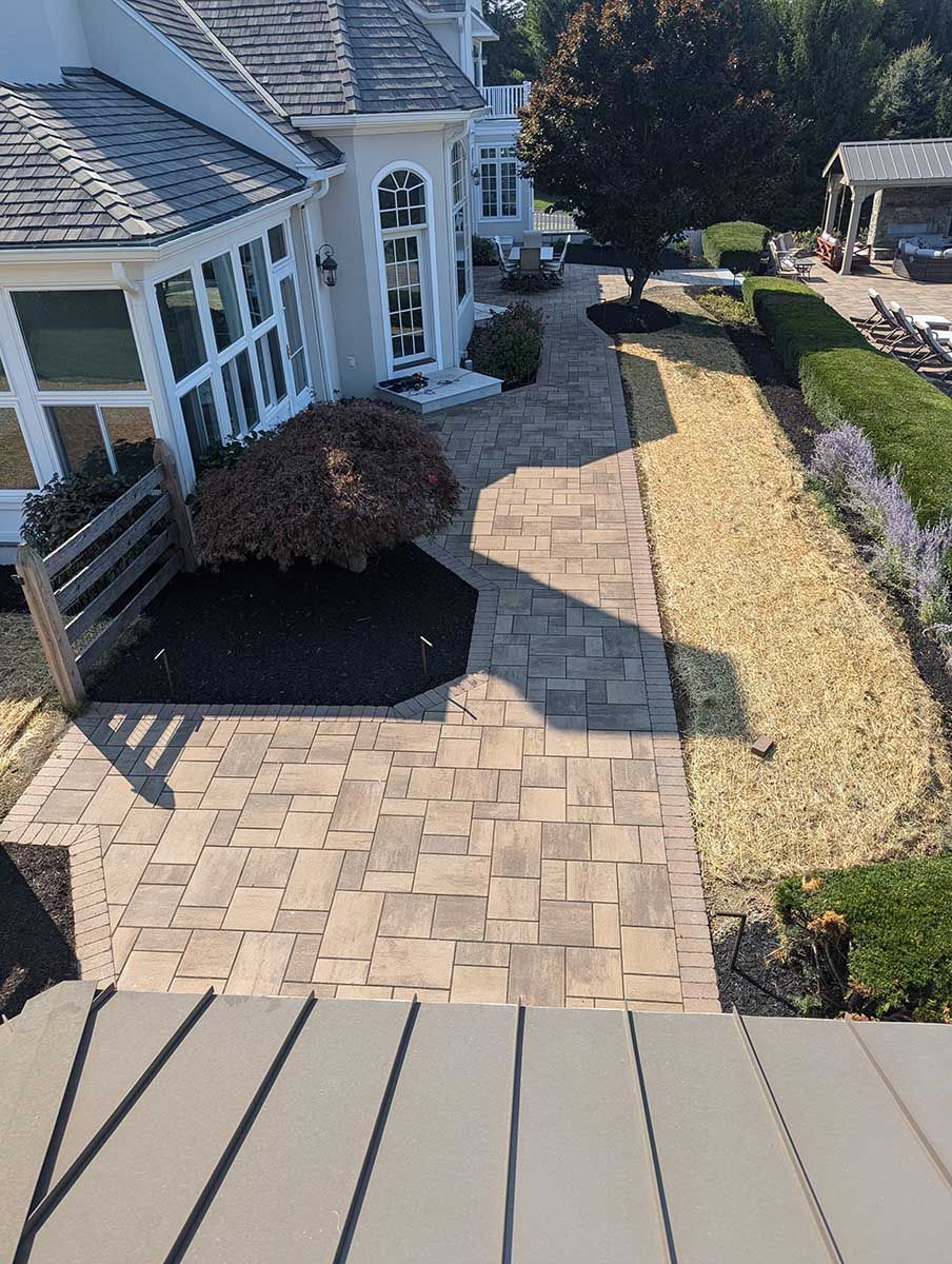 A large white house with a brick walkway leading to it.