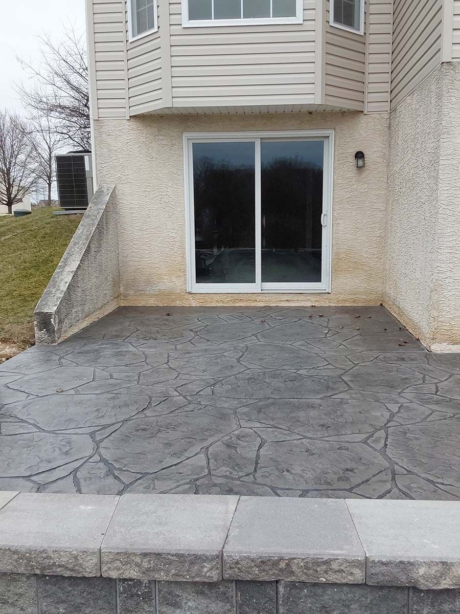 There is a patio in front of a house with sliding glass doors.