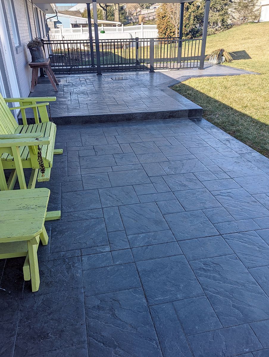 A patio with two green chairs and a table on it.