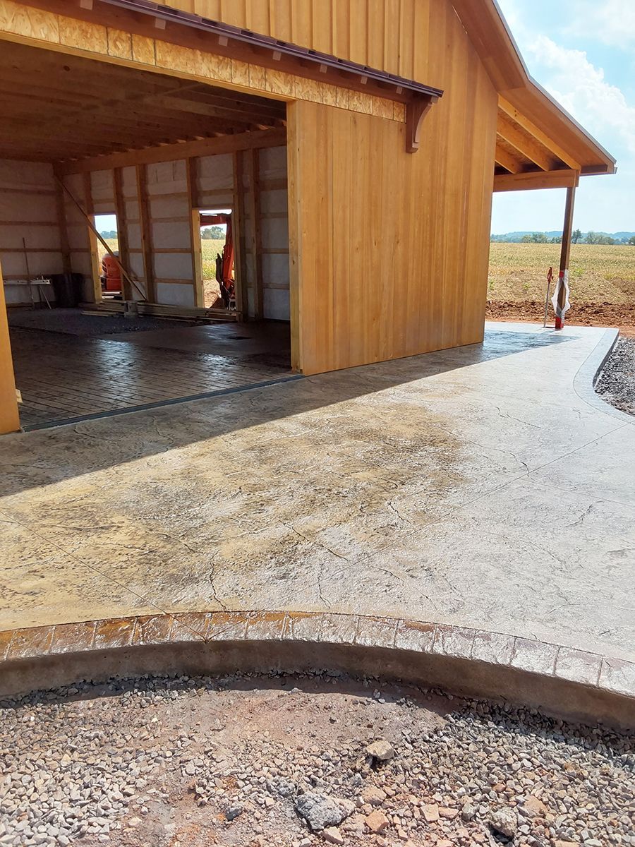 A wooden barn with a fire pit in front of it.