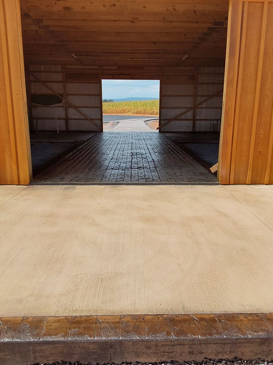 The inside of a barn with a concrete walkway leading to it.