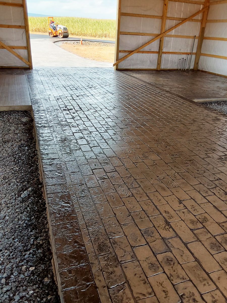 A brick floor in a building with a tractor in the background.