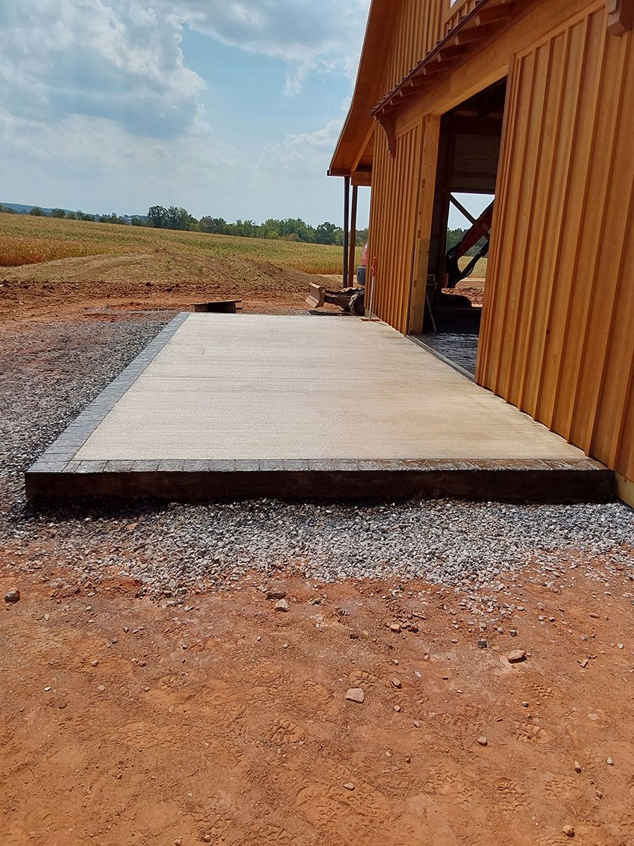 A large concrete slab is sitting in front of a wooden barn.