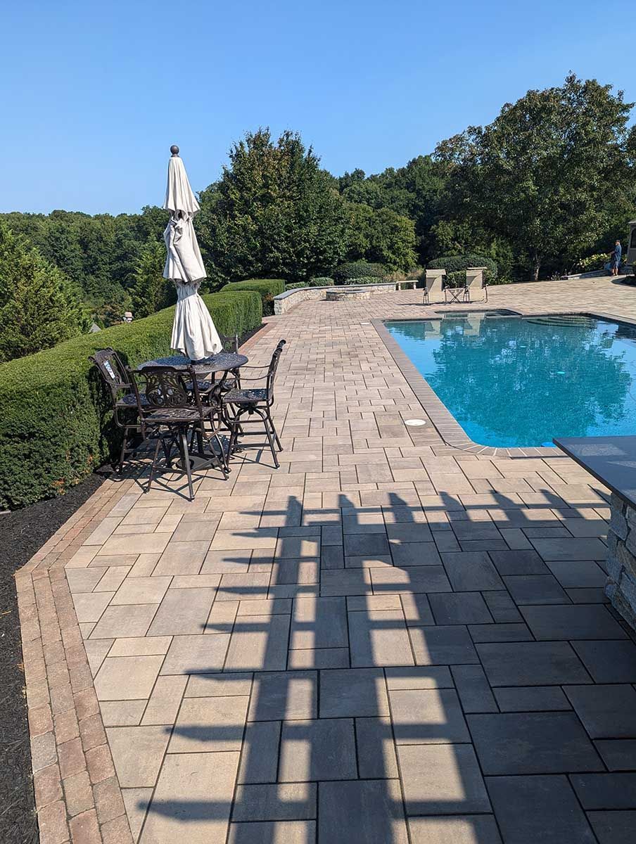 A patio with umbrellas and chairs next to a swimming pool