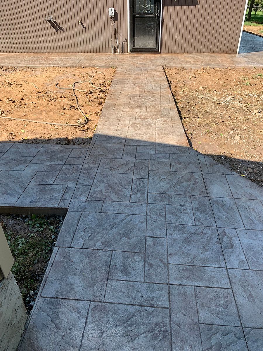 A concrete walkway leading to a house with a door.