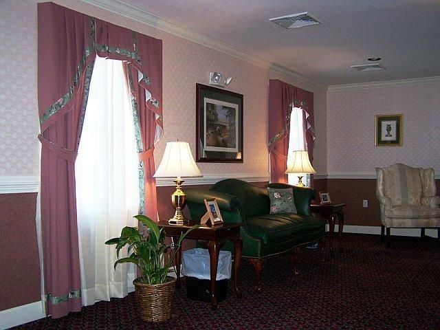 Interior with pink walls, window with pink curtains, green sofa, and lamps.