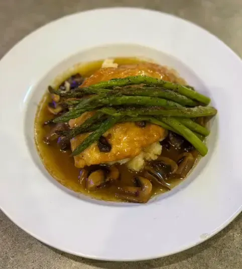 A plate of food with asparagus , mushrooms and mashed potatoes on a table.
