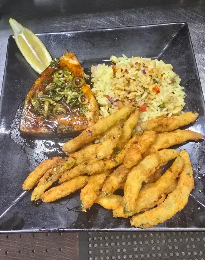 A black plate topped with fried food and rice