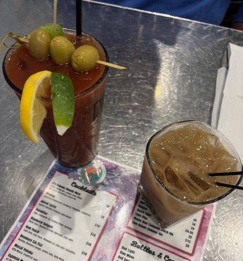 A glass of orange juice with a pink rubber duck on top of it.