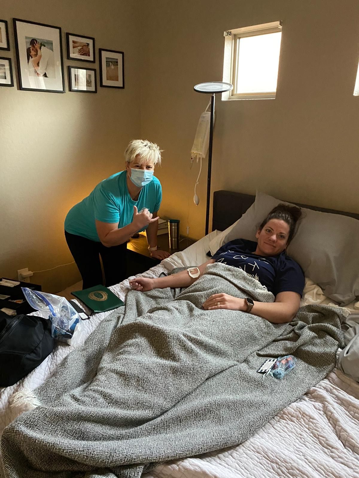 A woman is laying in a bed with a nurse standing next to her.