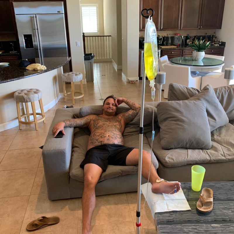 A man is laying on a couch with an iv in his arm