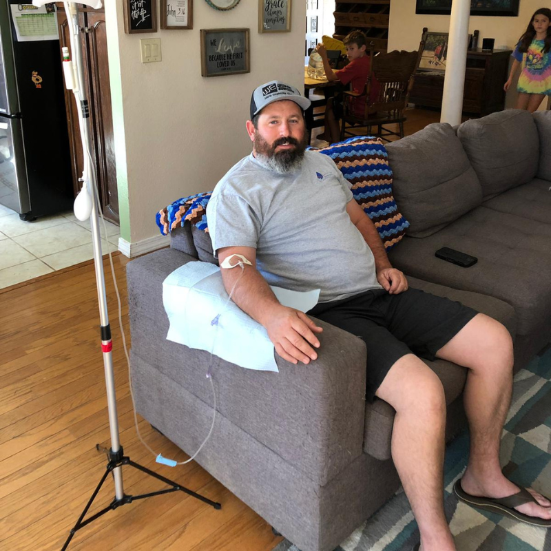A man is sitting on a couch with an iv in his arm