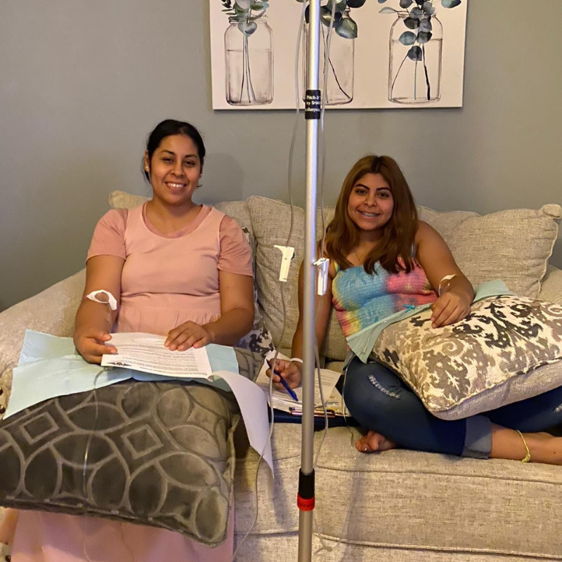 Two women are sitting on a couch with iv drips in their veins