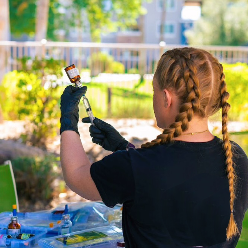 A woman with braids is holding a bottle of liquid in her hand.