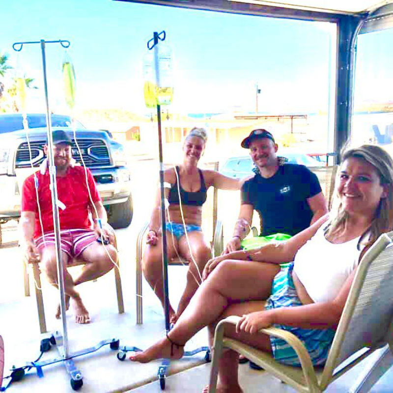 A group of people sitting in chairs with iv drips in them